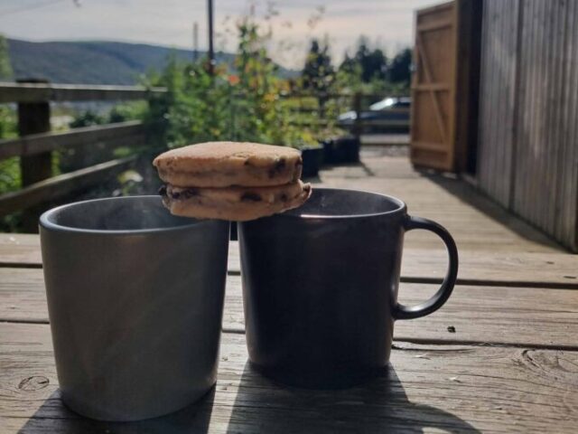 welsh cakes sat on two mugs with a view behind them