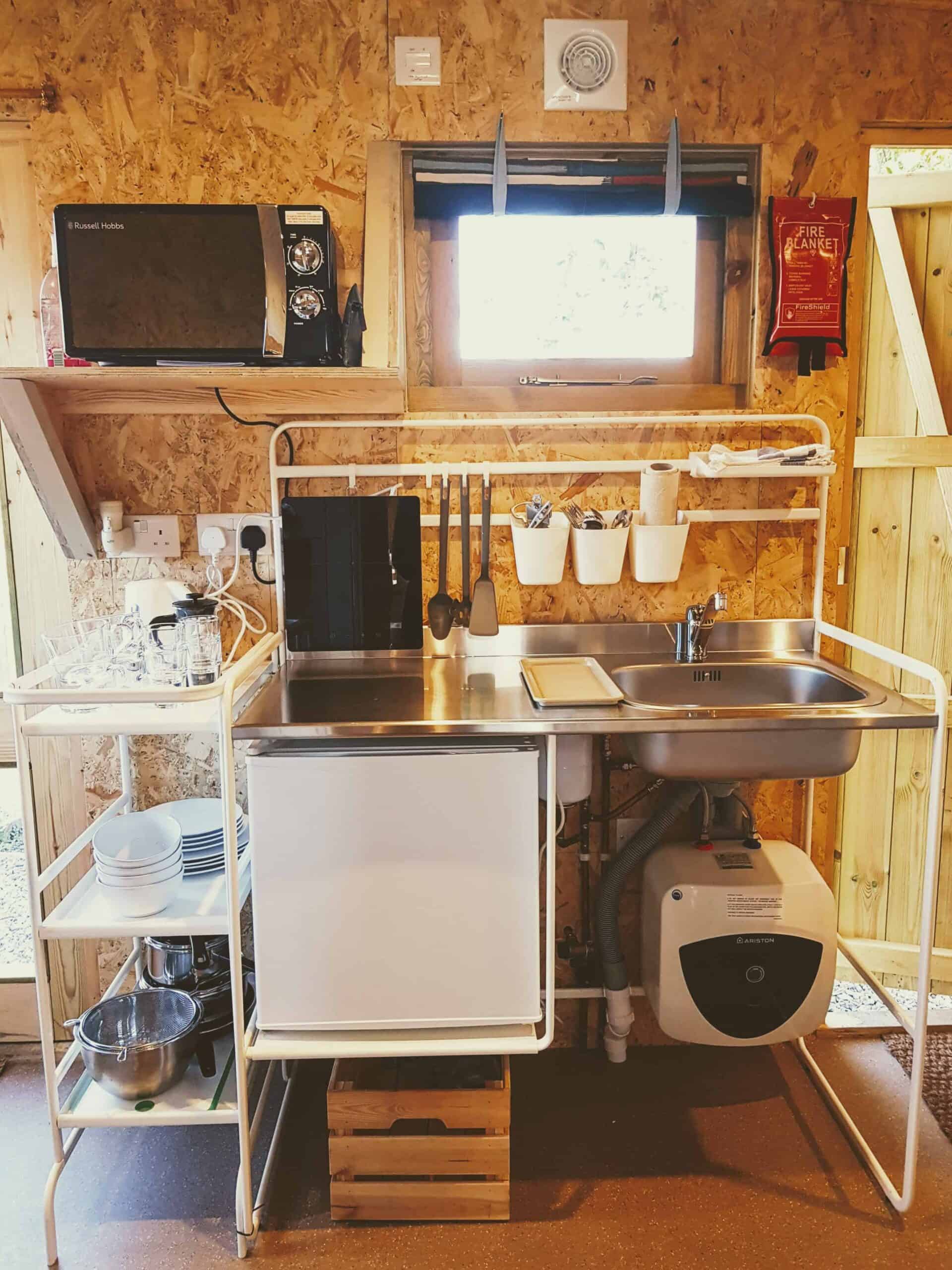 Cabin kitchenette with microwave, sink, hob, fridge, water heater, pots, pans, crockery