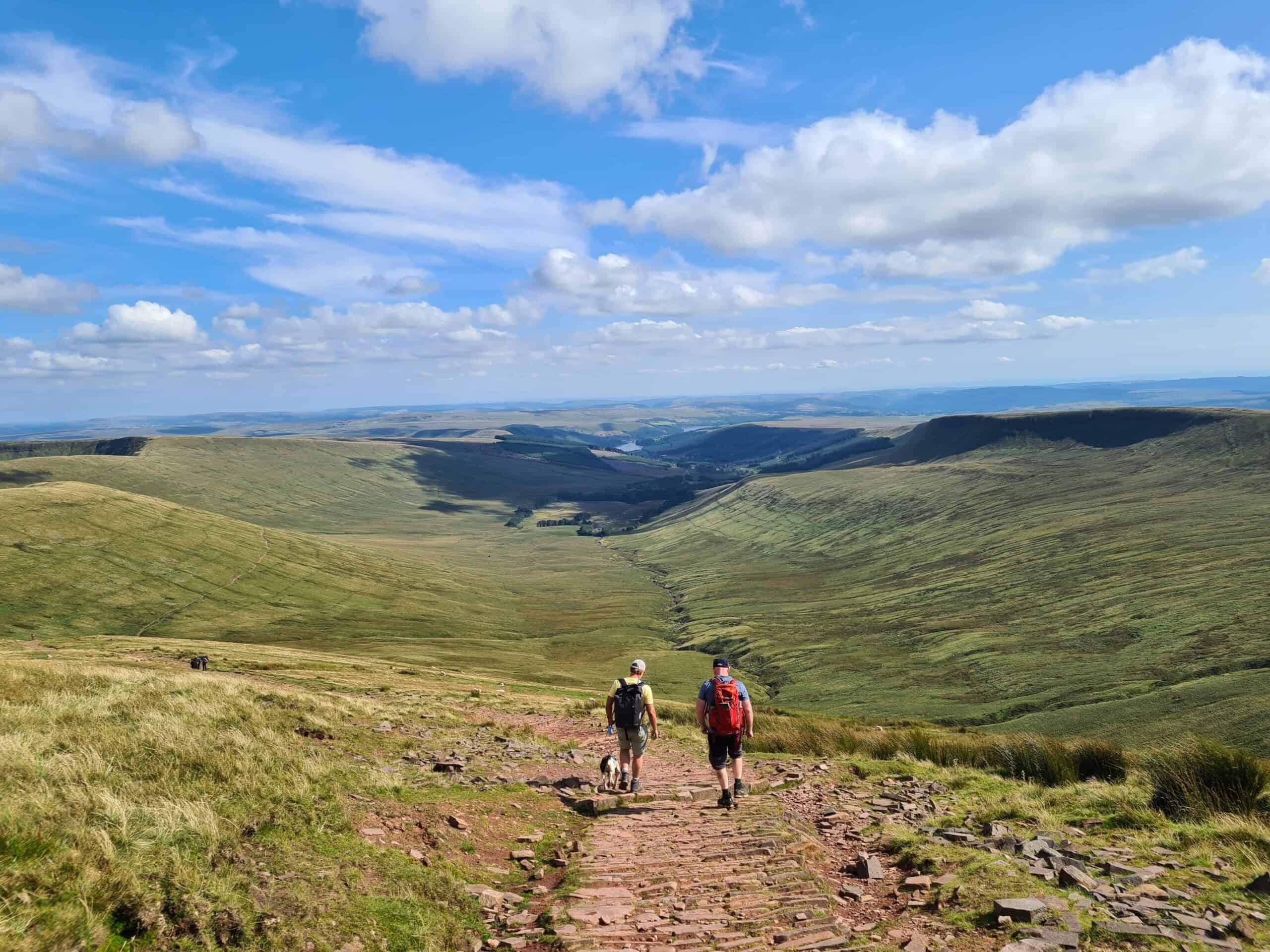 Two people walking down a trail from Pen y Fan in the Brecon Beacons