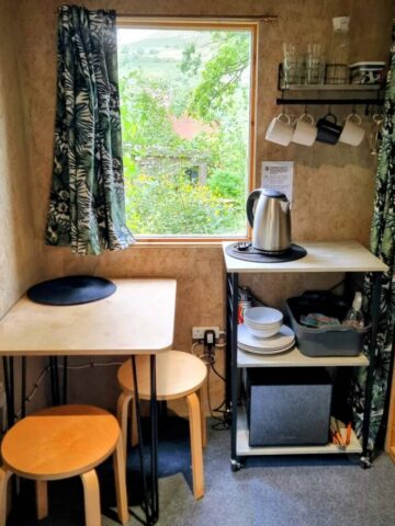 a table by a window with a kettle and crockery